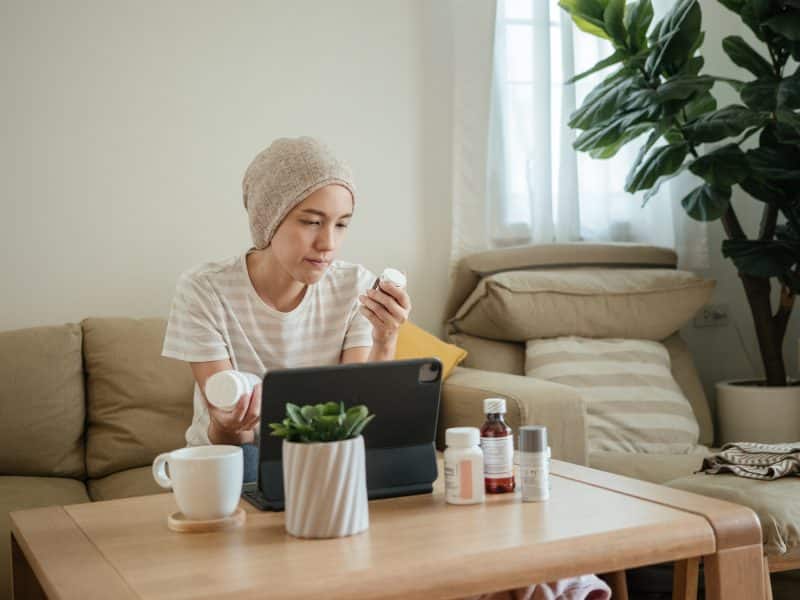 A young adult woman sits in her home in Los Angeles looking at the cancer medication prescribed to her.