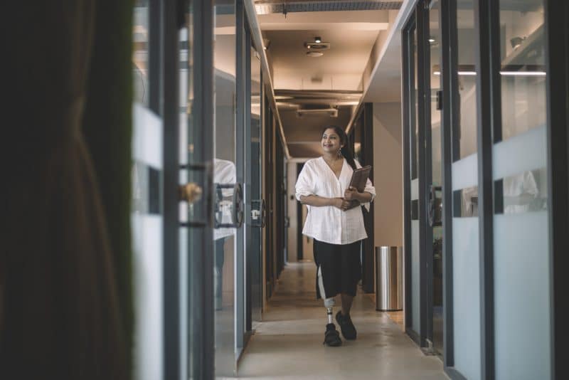 A woman with a prosthetic leg walking through an office.